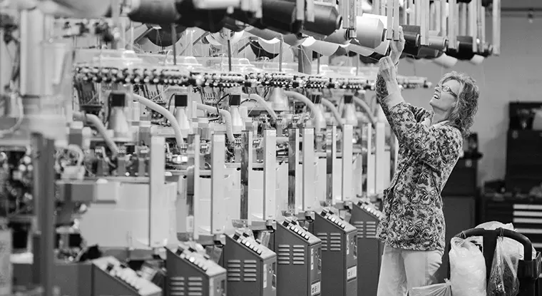 An employee at Nester Hosiery checks a knitting machine during production. 