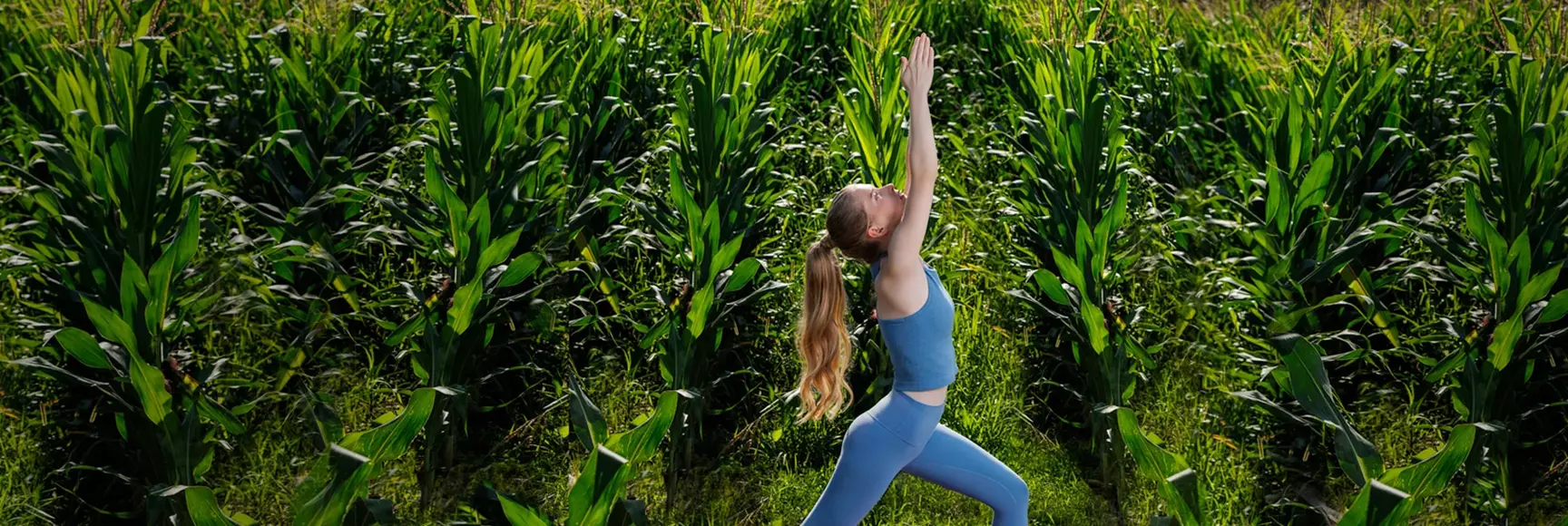 A woman in a cornfield in a yoga pose promotes The LYCRA Company’s bio-derived LYCRA® fiber made with QIRA® launching in 2025