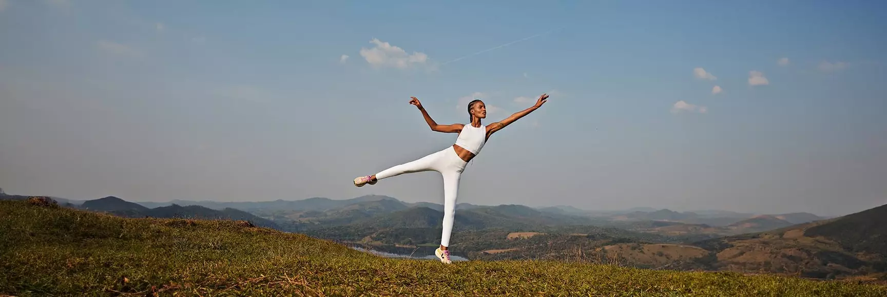 Model doing yoga on mountain in white athleisure clothing 