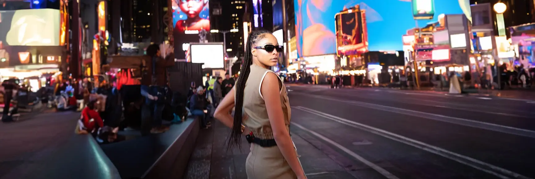 A model in a sleeveless tan dress in a city