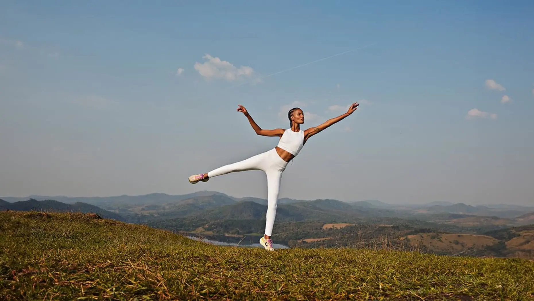 Model doing yoga on mountain in white athleisure clothing 